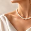 Collier en perles blanches au rendu nacré porté autour du cou