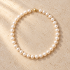 Collier en perles blanc nacre pose a plat avec fermoir dore